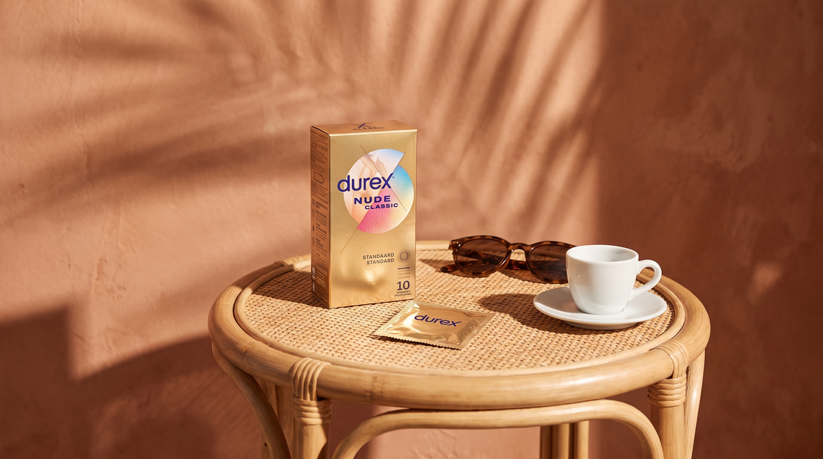 Durex Nude Classic condooms op een rotan bijzettafel met zonnebril en espresso in zomerlicht