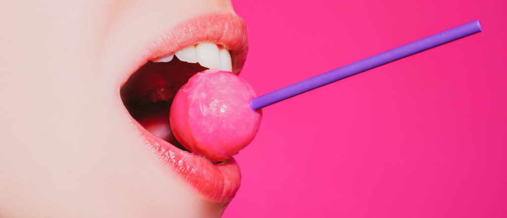 licking candy lollipop model woman lips sucking candy glamor sensual model with red lips eat sweats lolly pop isolated pink