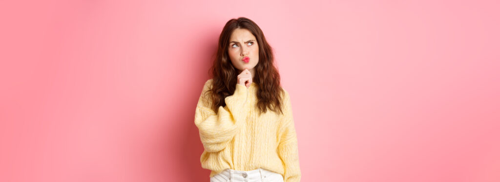 puzzled cute girl thinking touching chin frowning thoughtful looking aside logo banner with pensive face standing pink background