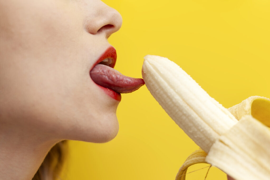 sexy intimate blowjob concept woman licks takes banana her mouth yellow background